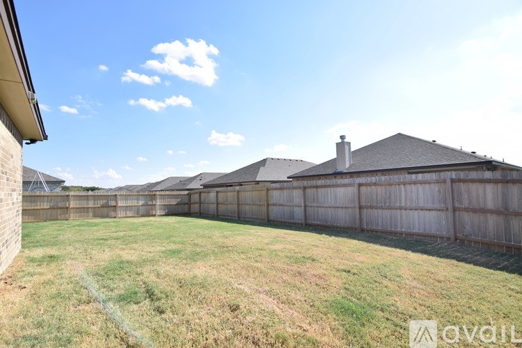 A backyard with a wooden fence and a house in the background.