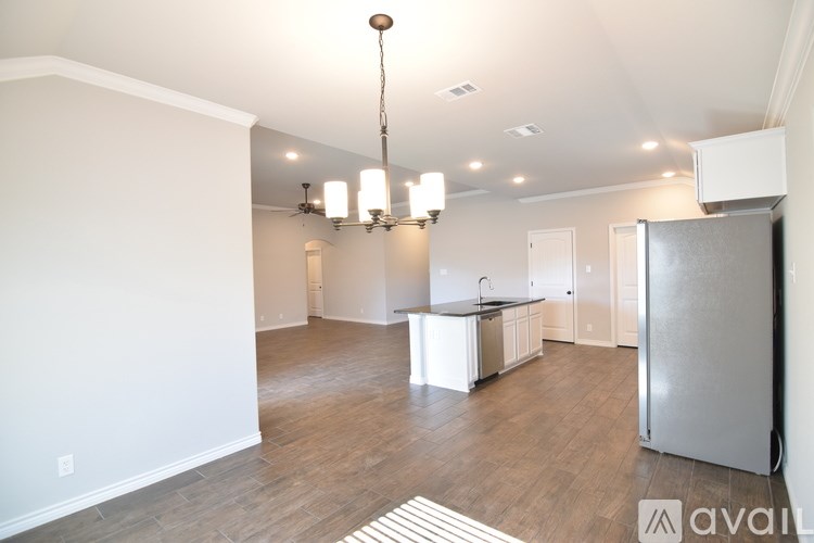 A kitchen area with a refrigerator, sink, and cabinets.