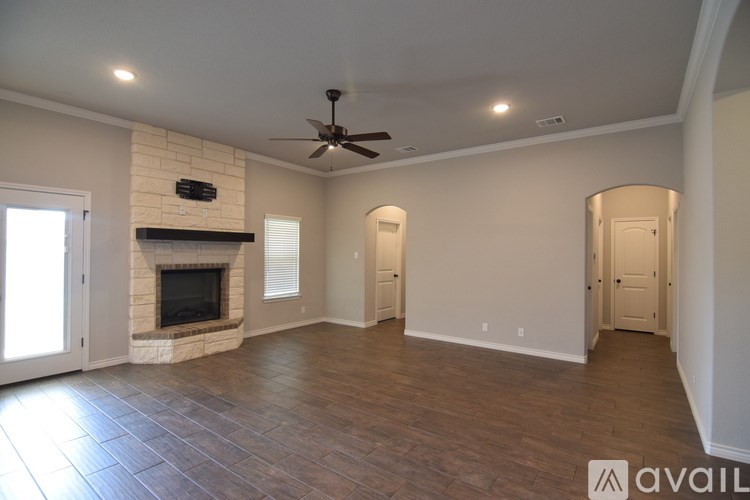 A spacious room with a fireplace and a ceiling fan.