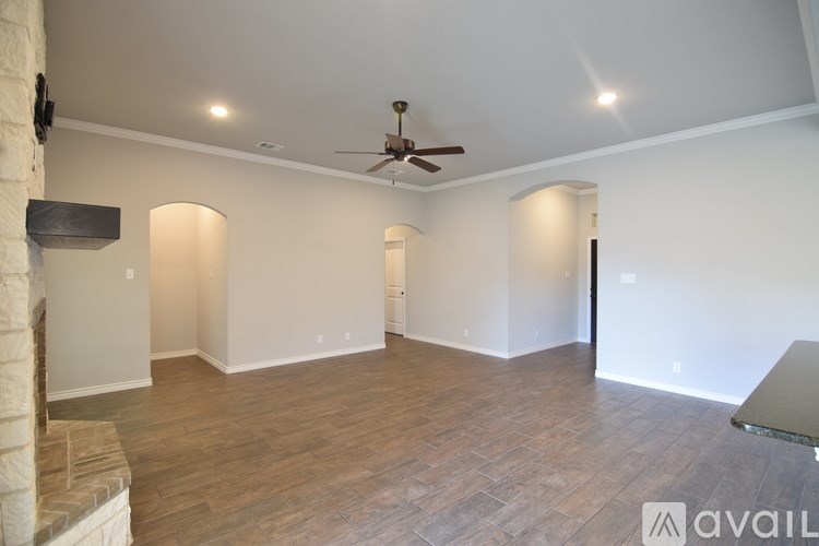 A spacious room with a ceiling fan and wooden flooring.