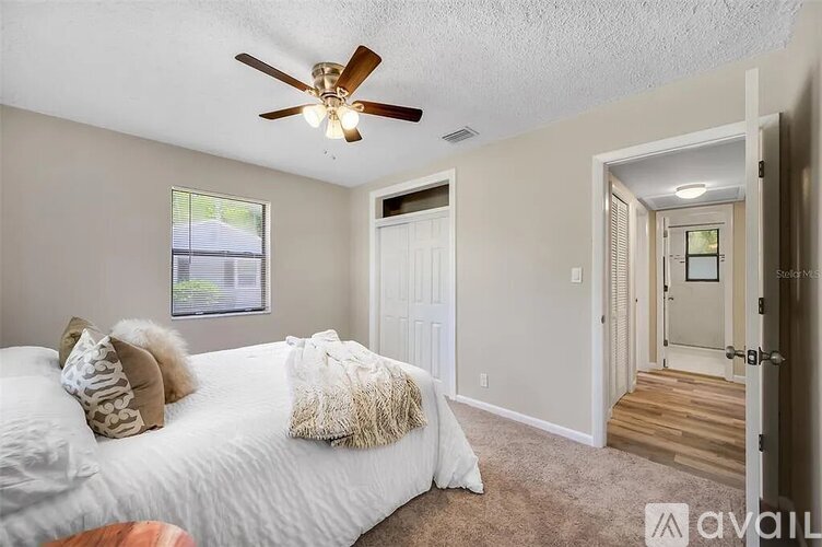 A bedroom with a white bed and a ceiling fan.