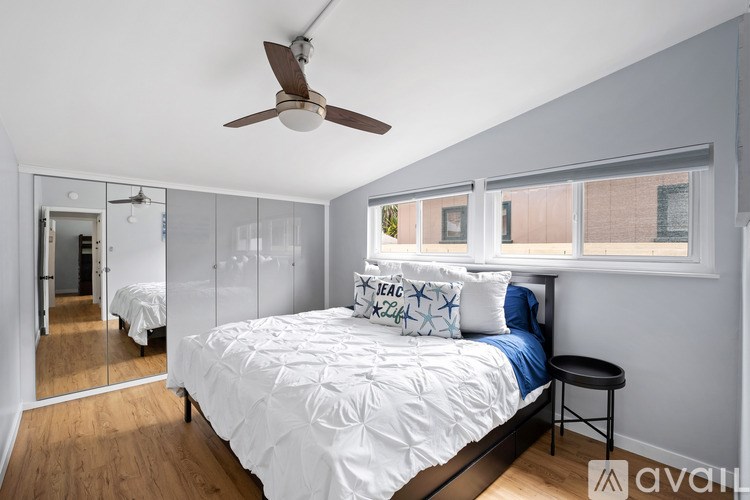 A bedroom with a bed, a ceiling fan, and a mirror.