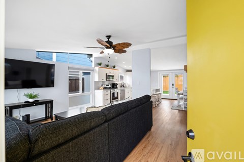 A living room with a black couch and a ceiling fan.