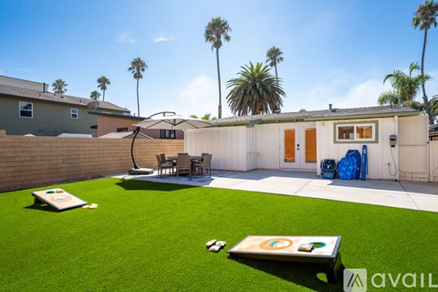 A backyard with a lawn, a table, chairs, and a pool table.