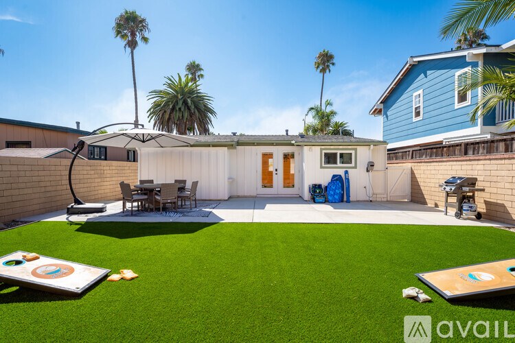 A backyard with a lawn, a patio, and a blue house.
