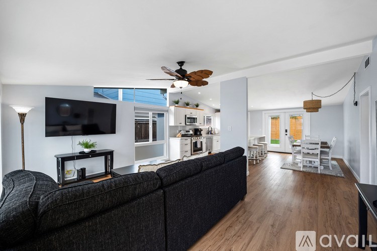 A living room with a black couch and a flat screen TV mounted on the wall.