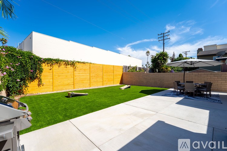 A backyard with a white fence and a yellow wall.