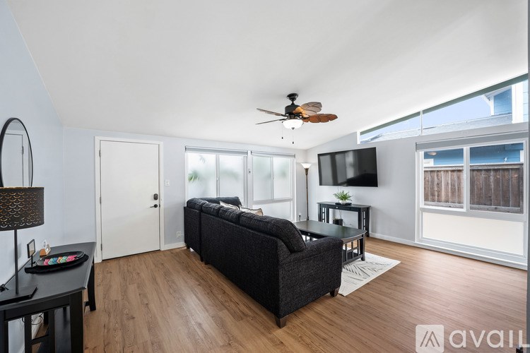 A living room with a black couch and a ceiling fan.
