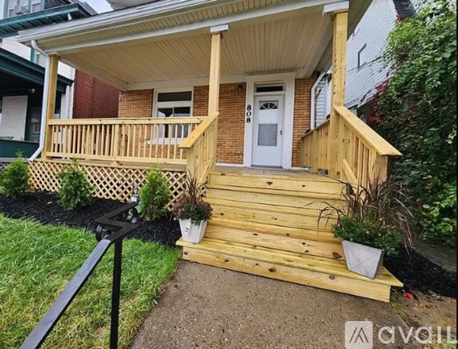 A wooden porch with a white door and a small front yard.