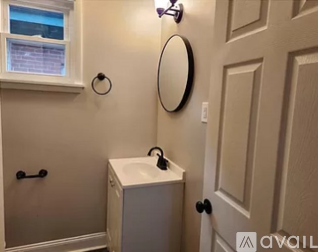 A bathroom with a white sink and a round mirror.
