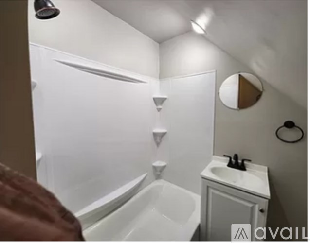 A small white bathroom with a sink and a shower.