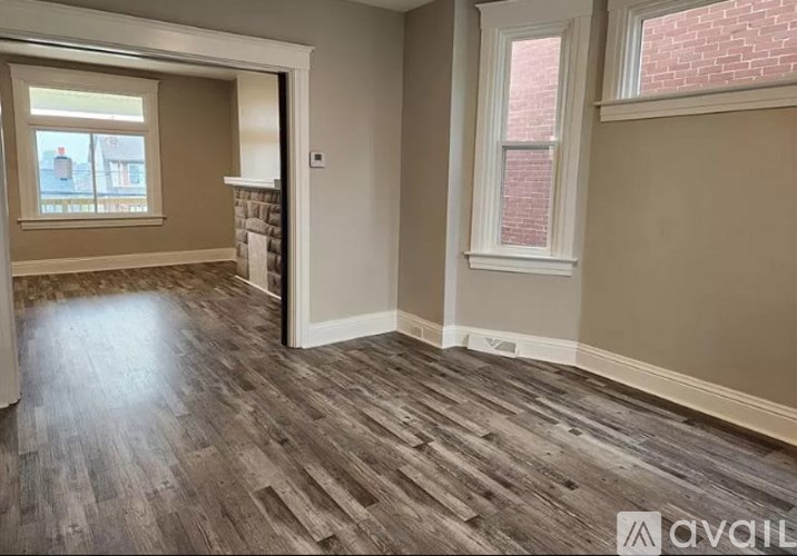 A room with wooden flooring and a window with a view of a street.