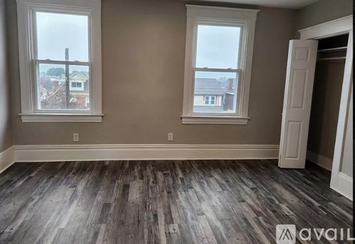 A room with two windows and wooden flooring.