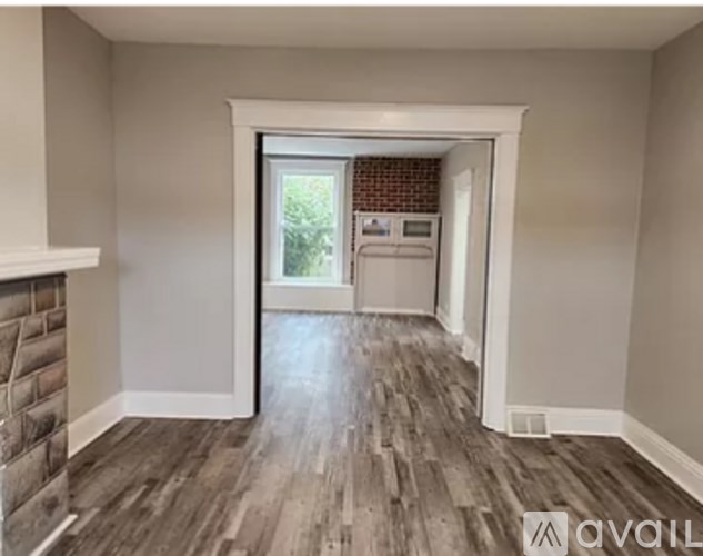 A room with a brick fireplace and wood flooring.