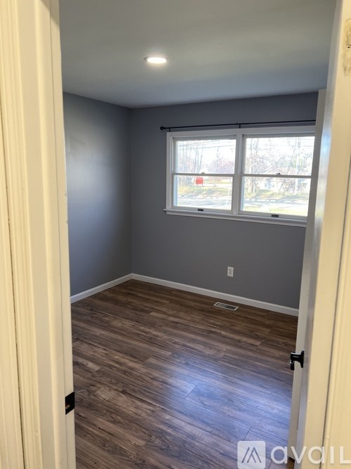 A room with a window and wooden flooring.
