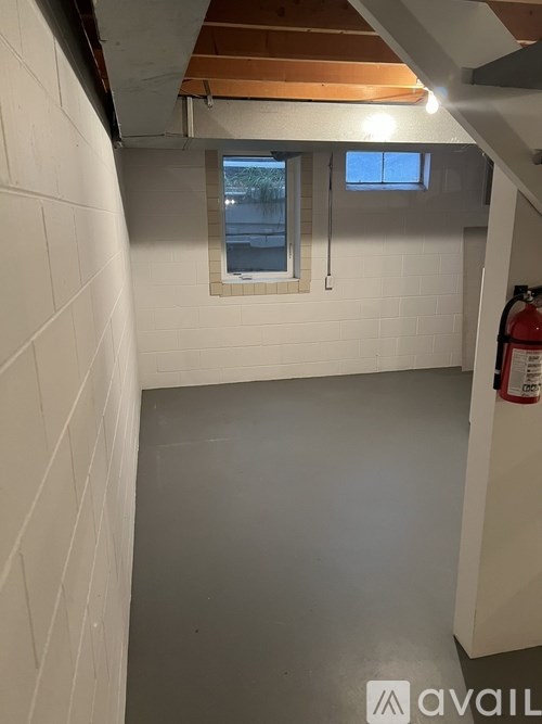 A white tiled room with a window and a fire extinguisher on the wall.