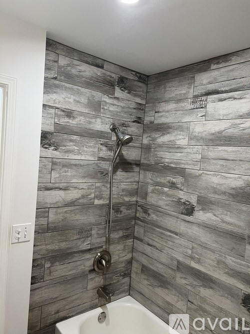 A bathroom with a grey tiled wall and a white sink.