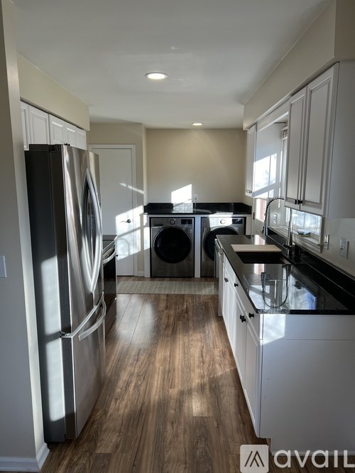A kitchen with a refrigerator, dishwasher, and washing machine.