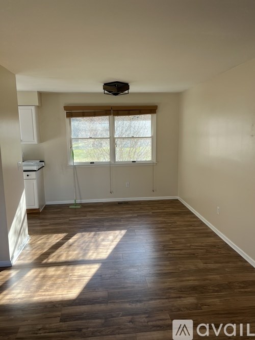 A room with wooden floors and a window with blinds.
