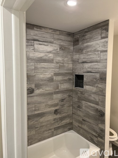 A bathroom with a wood grain tile wall.