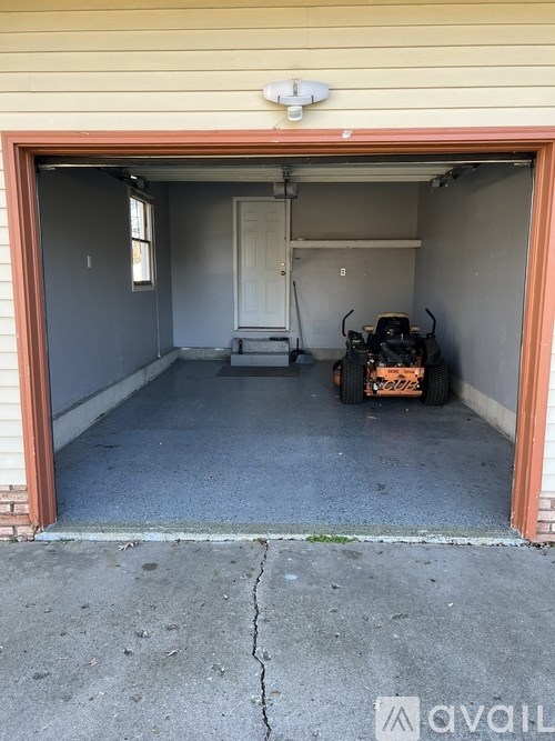 A garage with a chainsaw and a lawn mower in it.