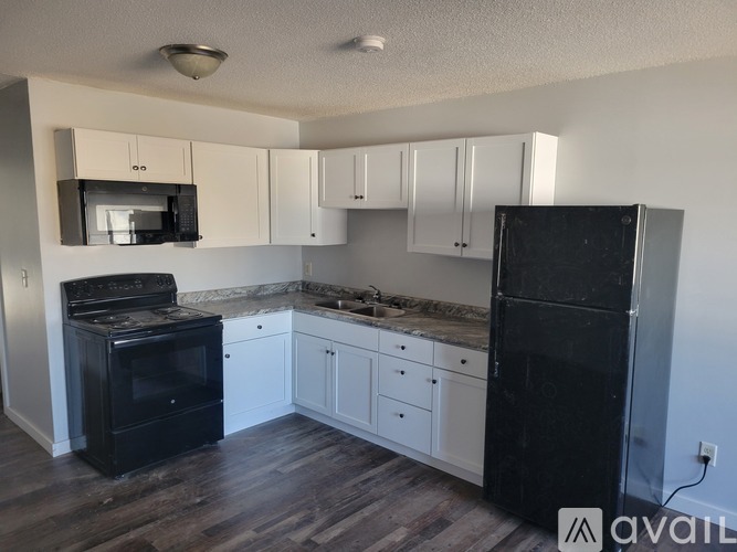 A kitchen with black appliances and white cabinets.