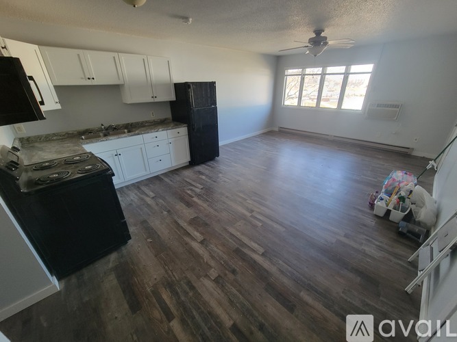 A kitchen with a black fridge and wooden floors.
