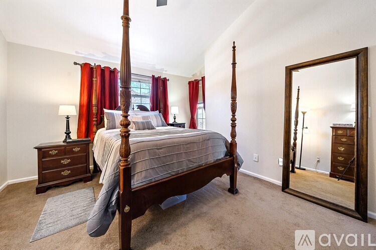 A bedroom with a four poster bed, a dresser and a mirror.
