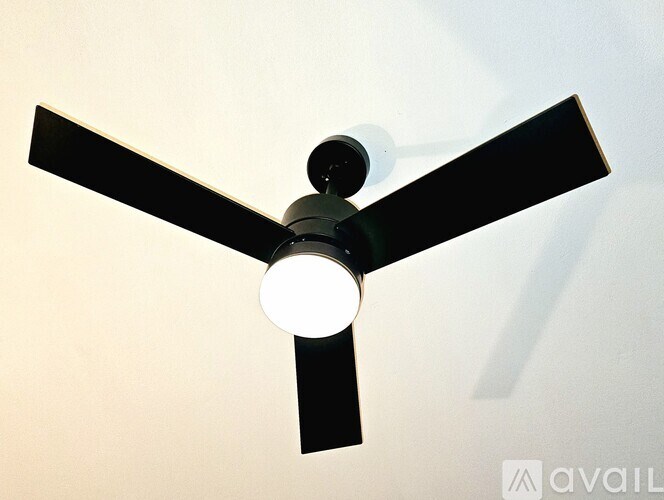 A ceiling fan with a light on, mounted on a white ceiling.