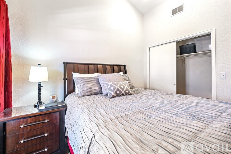 A bedroom with a bed, nightstand, and a red curtain.