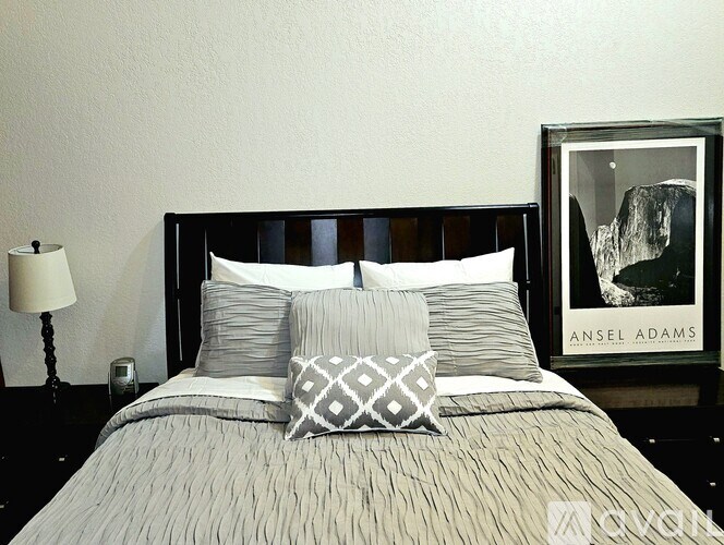 A bed with pillows and a picture of a mountain by Ansel Adams.