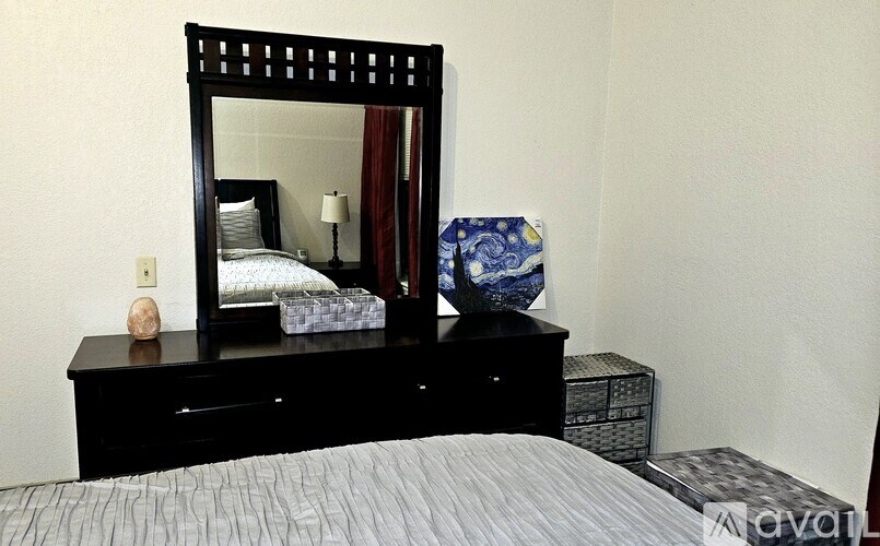 A bedroom with a large bed and a mirrored dresser.