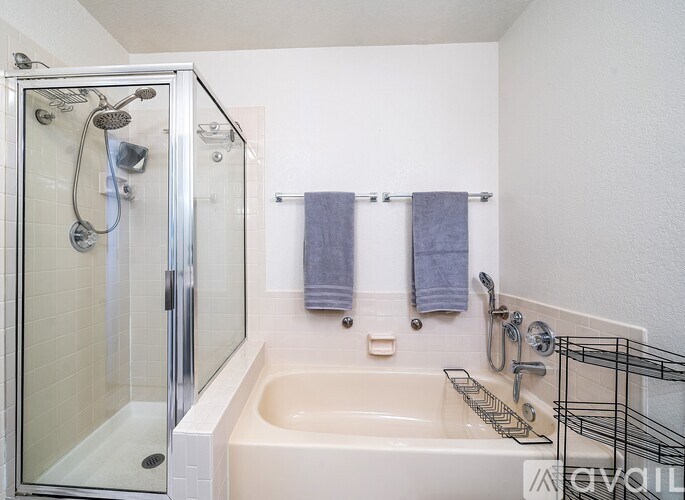 A white bathroom with a glass shower stall and a white tub.