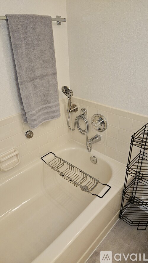 A bathroom with a white tub and a grey towel hanging on the shower rod.