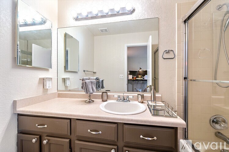A bathroom with a sink, mirror, and brown drawers.