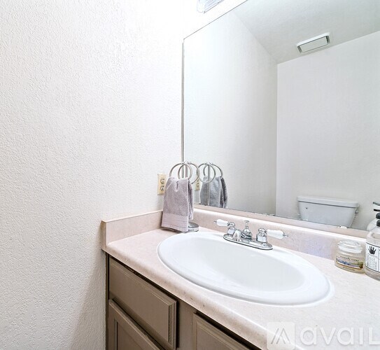 A bathroom sink with a white counter top and a white wall.