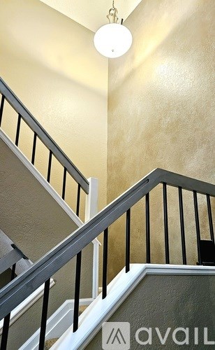 A staircase with a metal railing and a light hanging from the ceiling.