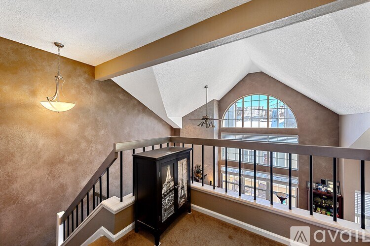 A staircase with a black railing and a light hanging from the ceiling.