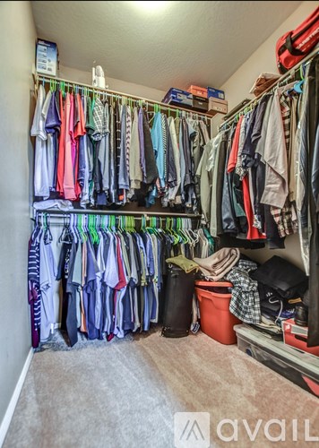 A small closet with a lot of clothes hanging on the rack.