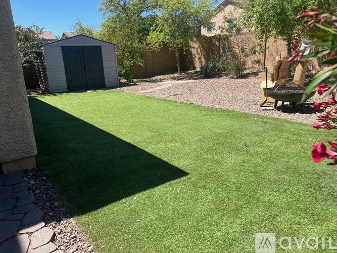 A backyard with a lawn, a shed, and a patio chair.
