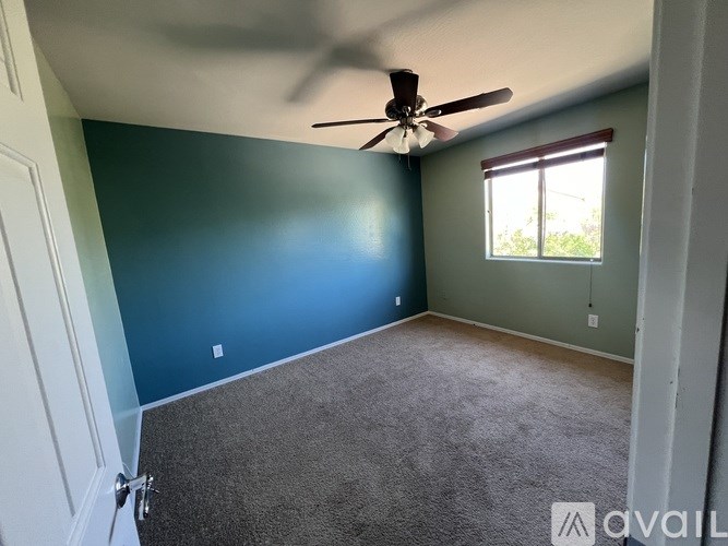 A room with a ceiling fan and carpeted floor.