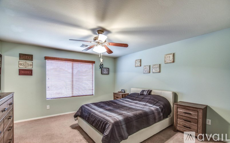 A bedroom with a bed, dresser, and ceiling fan.