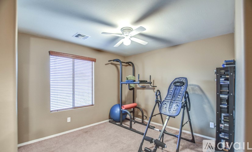 A room with a ceiling fan, a window with blinds, and exercise equipment.