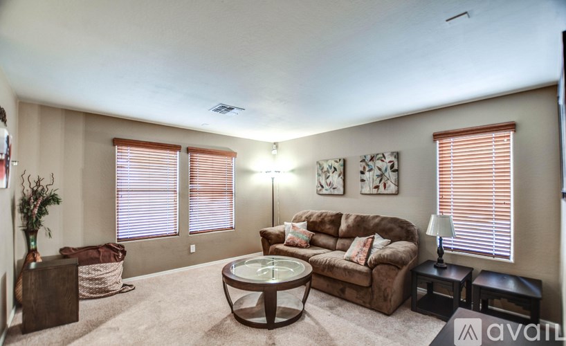 A living room with a brown couch, a glass coffee table, and two lamps.