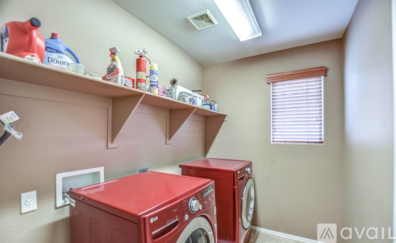 A laundry room with a red washer and dryer.