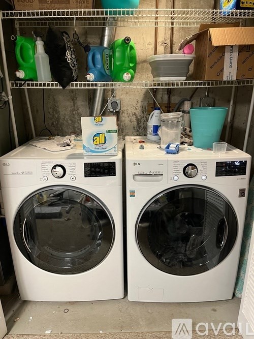 Two front loading washing machines in a cluttered laundry room.