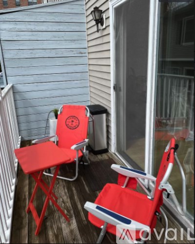 Two red chairs with white and blue trim are on a wooden deck.