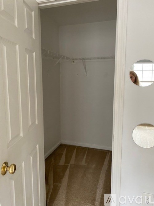 A white door with a gold handle and a round window on the right side.