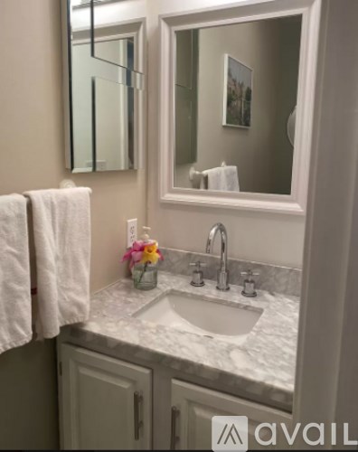 A bathroom with a sink, mirror, and towel.