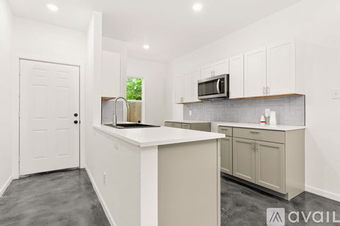 A kitchen with white cabinets and a white door.